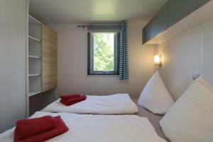 two beds in a small room with a window at Landgut Voigtsmühle in Friedland