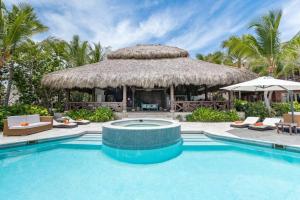 um resort com uma piscina e uma cabana de palha em CALETON 8 9 ACCESS TO EDEN ROC BEACH CLUB CHEF BUTLER MAiD GOLF CARTS POOLS JACUZZI em Punta Cana