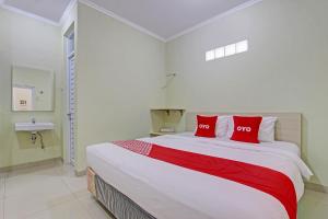 - une chambre avec un grand lit et des oreillers rouges dans l'établissement OYO 92642 Tumesa Homestay 2 Syariah, à Semarang