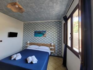 Un dormitorio con una cama azul con toallas blancas. en Mamalù en Lampedusa