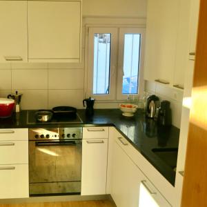 a kitchen with white cabinets and a stove top oven at Casa Segnas in Disentis