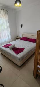 a bedroom with a bed with red pillows and avertisement at Nika Apartments in Ulcinj