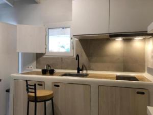kuchnia z białymi szafkami, umywalką i oknem w obiekcie Apartamento Caolin Rocabella w mieście El Chorro