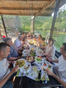 een groep mensen die rond een tafel eten bij Apartmani Karučki krš in Podgorica