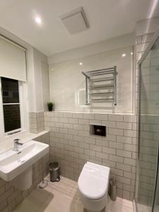 a white bathroom with a toilet and a sink at Notting Hill House in London