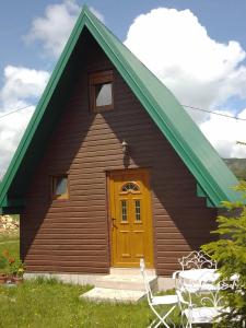 une maison avec une porte jaune et un toit vert dans l'établissement Etno Koliba Nikoleta, à Žabljak