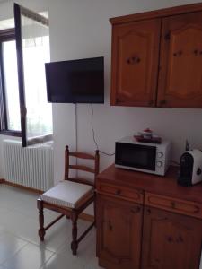 ein Wohnzimmer mit einer Mikrowelle und einem Stuhl in der Unterkunft Appartamento vacanza il Picchio Rosso in Mantello