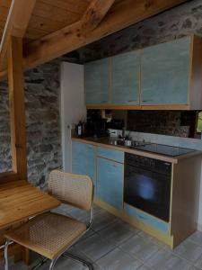 cocina con armarios azules, mesa y fogones en Rustico Leoro, en Ponte Brolla