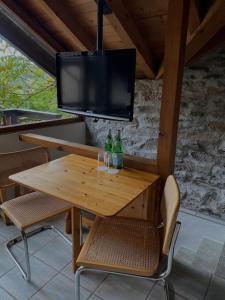 einen Holztisch mit 2 Flaschen und einen TV in der Unterkunft Rustico Leoro in Ponte Brolla