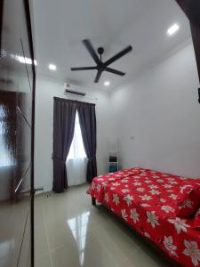 een slaapkamer met een rood bed en een plafondventilator bij Homestay2 Tok Bali in Pasir Puteh