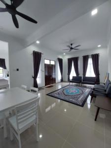 een woonkamer met een plafondventilator en een tafel en stoelen bij Homestay2 Tok Bali in Pasir Puteh