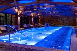 a large swimming pool with blue lighting in a building at Aries Hotel & SPA Zakopane in Zakopane