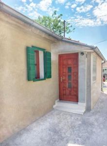 uma casa com uma porta vermelha e persianas verdes em Guest house Ana em Drnis