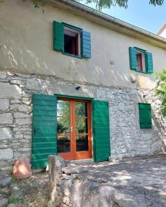 uma casa de pedra com portas e janelas verdes em Guest house Ana em Drnis