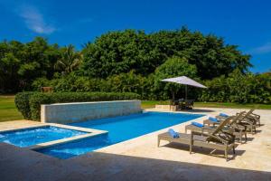 a swimming pool with lounge chairs and an umbrella at LAS CANAS 20 POOL JACUZZI GAMES HIBACHi STAFF in La Romana