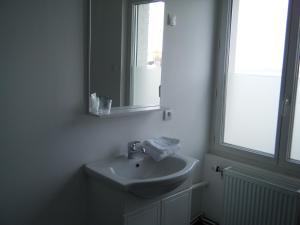 a white bathroom with a sink and a mirror at L'univers in Grand-Fort-Philippe