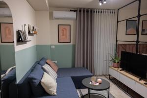 un salon avec un canapé bleu et une télévision dans l'établissement Three doors apartments, Strawberry Studio, à Tirana