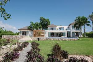 een groot huis met een groen gazon ervoor bij VILLA BELLA LUNA WITH CHEF MAiD GOLF CART AND POOL in Punta Cana