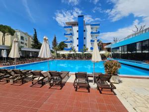 a pool with chairs and umbrellas in front of a hotel at SunBorn Hotel in Golem +81 photos