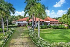 una casa con palmeras frente a un patio en INGENIO 9 TOP RATED VILLA WiTH POOL GOLF CARTS STAFF, en La Romana