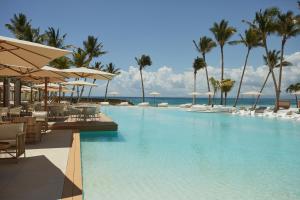 a swimming pool with chairs and umbrellas and the ocean at Cayo Levantado Resort - All Inclusive in Santa Bárbara de Samaná