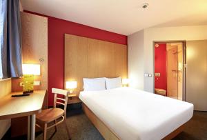 a bedroom with a large white bed and a desk and a chair at B&B HOTEL Toruń in Toruń