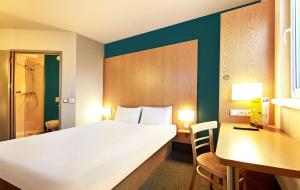 um quarto de hotel com uma cama grande, uma secretária e uma cadeira em B&B HOTEL Toruń em Toruń