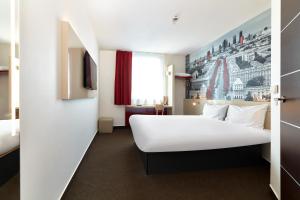 una habitación de hotel con una gran cama blanca y una ventana en B&B Hotel Warszawa-Okęcie, en Varsovia