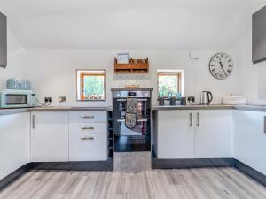 a kitchen with white cabinets and a clock on the wall at Red Brick Barn - Uk39916 in Howell