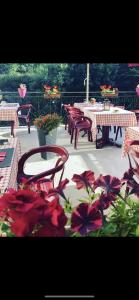 un patio con mesas, sillas y flores rojas en La renaissance, en Saint-Cirgues-en-Montagne