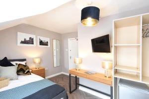 um quarto com uma cama e uma secretária com uma televisão em Anam Cara House - Guest Accommodation close to Queen's University em Belfast