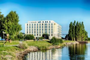 um edifício ao lado de um rio com um edifício em B&B Hotel Wilhelmshaven em Wilhelmshaven