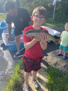 a young boy holding a fish in his hands at Ladd Pond Cabins and Campground, LLC in Colebrook