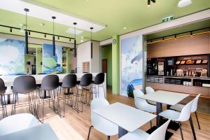 un bar con tavoli e sedie bianchi in un ristorante di B&B Hotel Villach a Villach