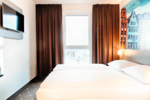 2 Betten in einem Hotelzimmer mit Fenster in der Unterkunft B&B Hotel Rostock City-West in Rostock