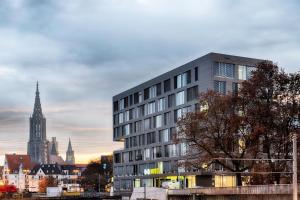 ein hohes Gebäude mit einem Uhrturm in einer Stadt in der Unterkunft B&B Hotel Ulm in Ulm