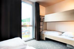 a bedroom with two bunk beds and a window at B&B Hotel Stuttgart-Neckarhafen in Stuttgart