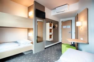 a hotel room with two beds and a desk at B&B Hotel Stuttgart-Neckarhafen in Stuttgart