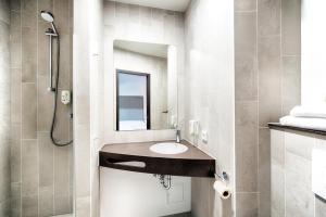 La salle de bains est pourvue d'un lavabo et d'une douche. dans l'établissement B&B Hotel Stuttgart-Neckarhafen, à Stuttgart