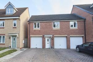 a brick house with four garage doors on a brick driveway at Vert Vale Apartment in Newcastle upon Tyne