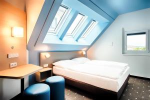 a bedroom with a bed and a table and windows at B&B Hotel Wien-Meidling in Vienna