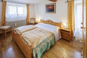 a bedroom with a bed and two tables and two windows at Villa Casanova - Stayincortina in Cortina dʼAmpezzo