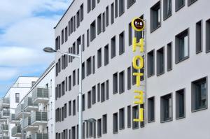 un edificio blanco alto con un letrero amarillo. en B&B Hotel Wien-Hbf, en Viena