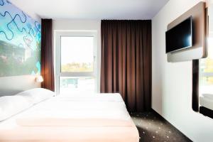 B&B Hotel Ravensburg في رافنسبرغ: غرفة فندقية بسريرين وتلفزيون بشاشة مسطحة