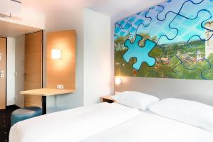 B&B Hotel Ravensburg في رافنسبرغ: غرفة نوم بسريرين وقطعة لغز على الحائط