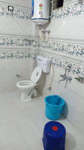 ein Badezimmer mit Toilette und blauem Eimer in der Unterkunft Shanti Jungle cottage in Mashobra