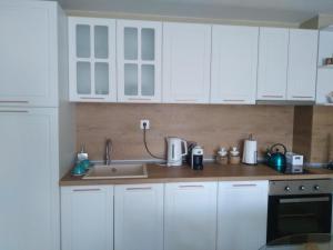 una cocina con armarios blancos y fregadero en Апартамент Яница, en Razlog