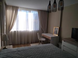 1 dormitorio con cama, escritorio y ventana en Апартамент Яница, en Razlog