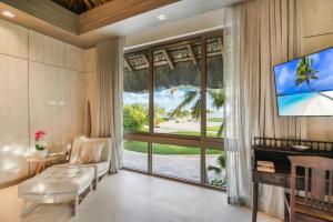 a living room with a large window and a tv at Caleton 16 Ocean view 5 bedroom villa with Chef Butler Maid Golf Cart in Punta Cana