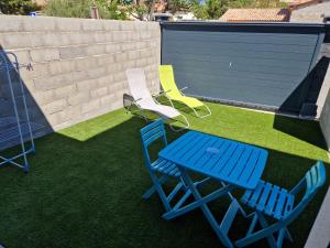 three chairs and a blue table and chairs on a lawn at Chez Nadia in Montpeyroux